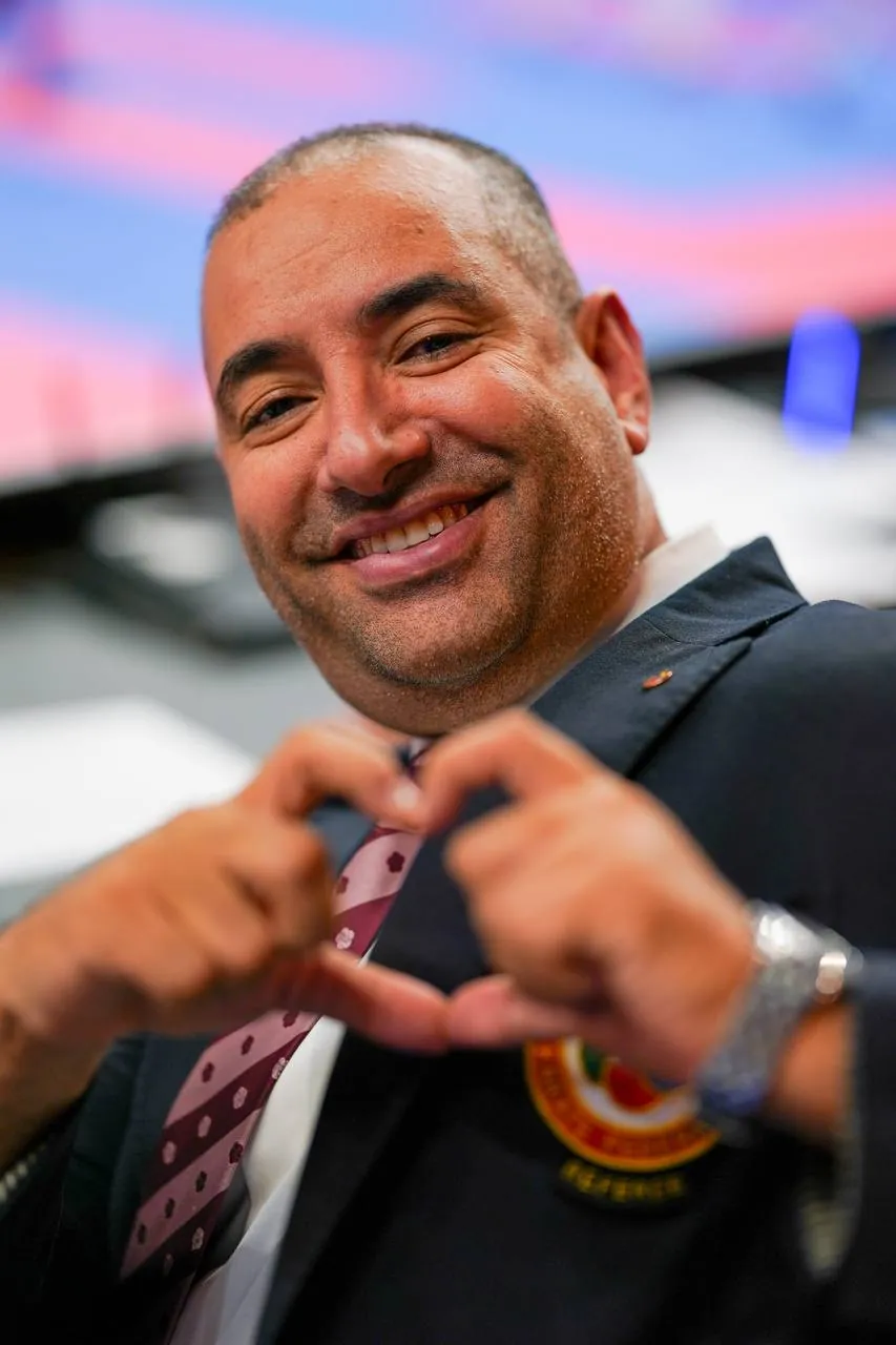 A team official makes a heart with his hands
